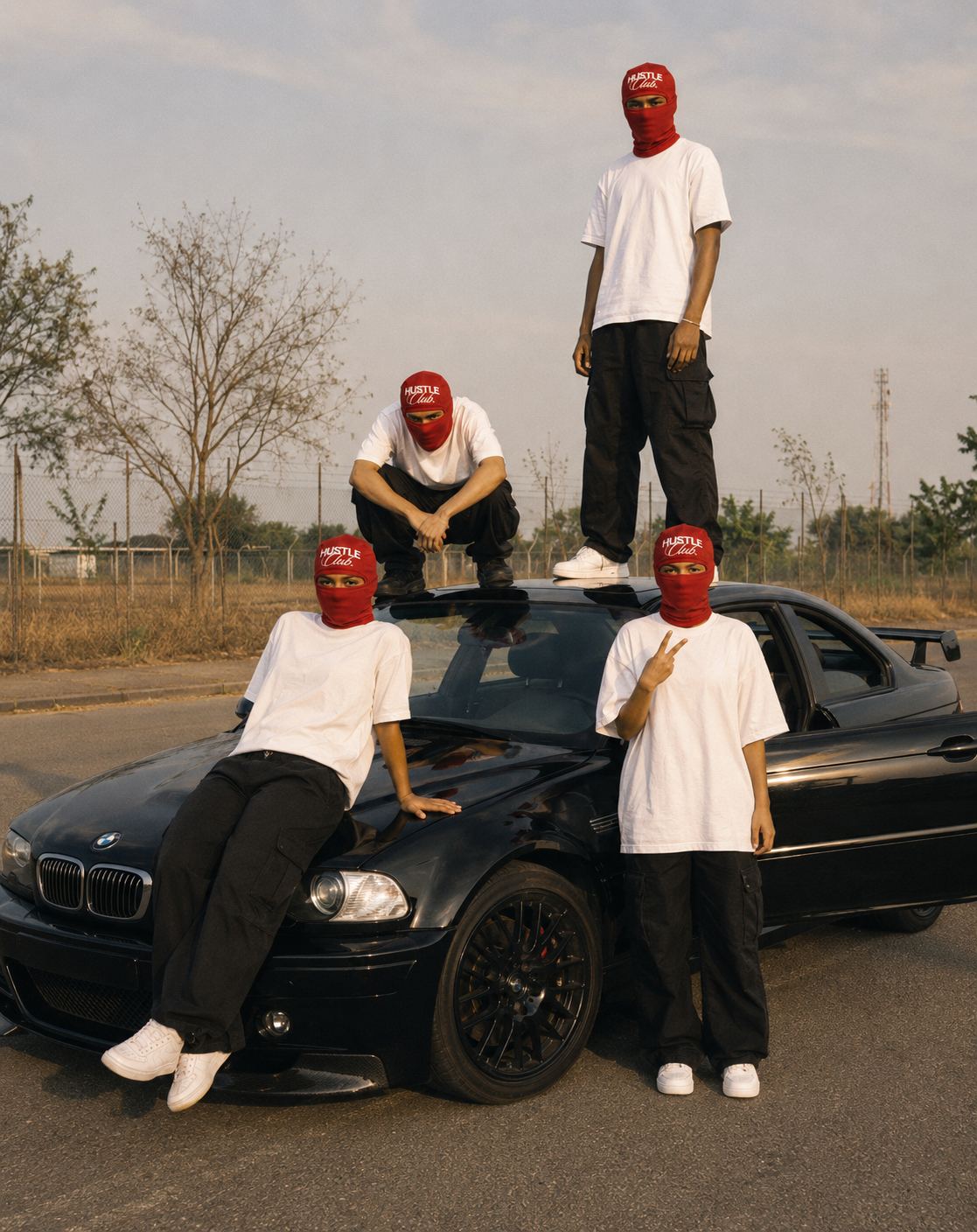Quatre modèles en cagoule rouge posant sur et autour d'une BMW noire.