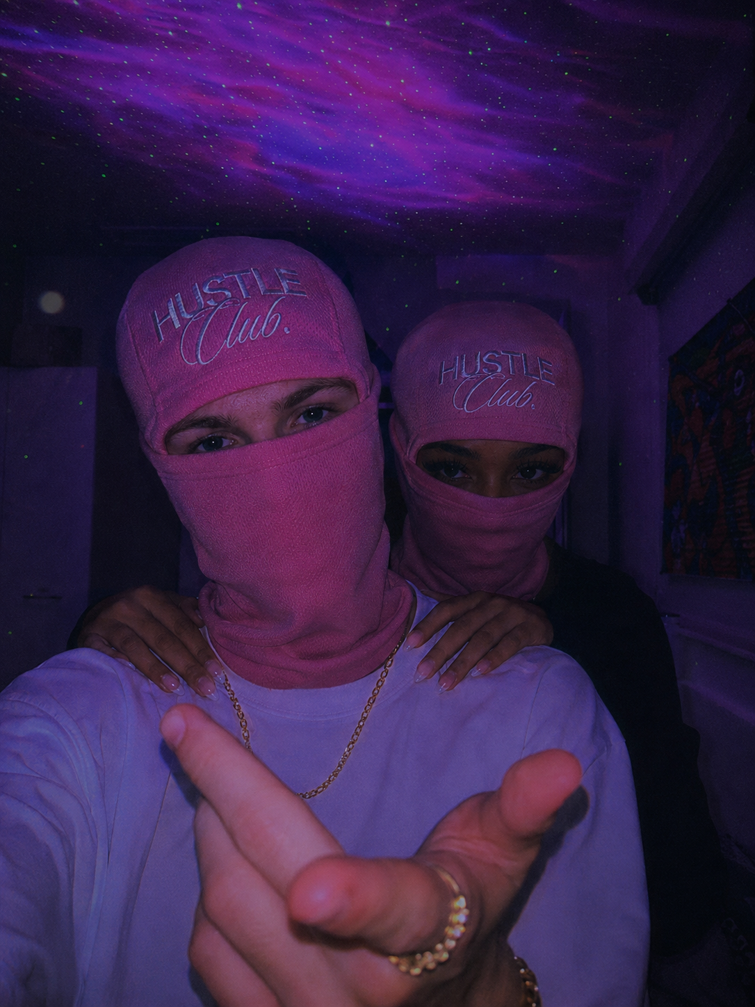 Couple en cagoules roses sous un plafond étoilé violet.